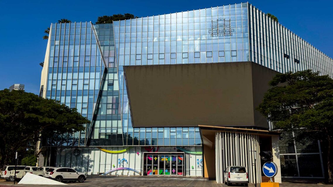 Photo of a glass office building with the outline of a removed Prince Group logo on the facade.