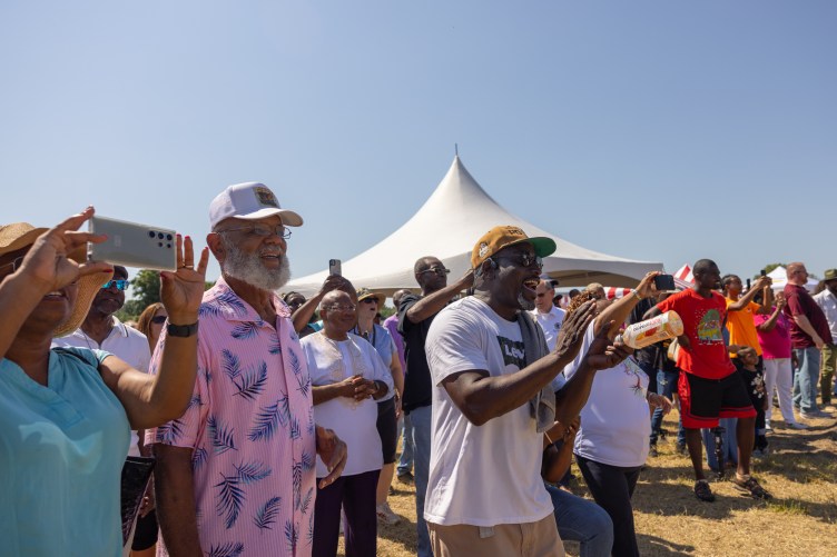 People standing outside clap, cheer and record with their phones.
