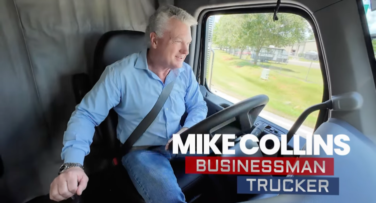 A smiling man wearing a long-sleeve button-down and jeans drives inside of a truck cab with an overlay of text: “Mike Collins: Businessman Trucker.”