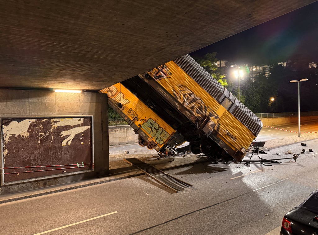 Two cars of a freight train which derailed after a collision, fell off a bridge and lay on a road in Munich on Saturday. Photo: Reuters Two cars of a freight train which derailed after a collision, fell off a bridge and lay on a road in Munich on Saturday. Photo: Reuters