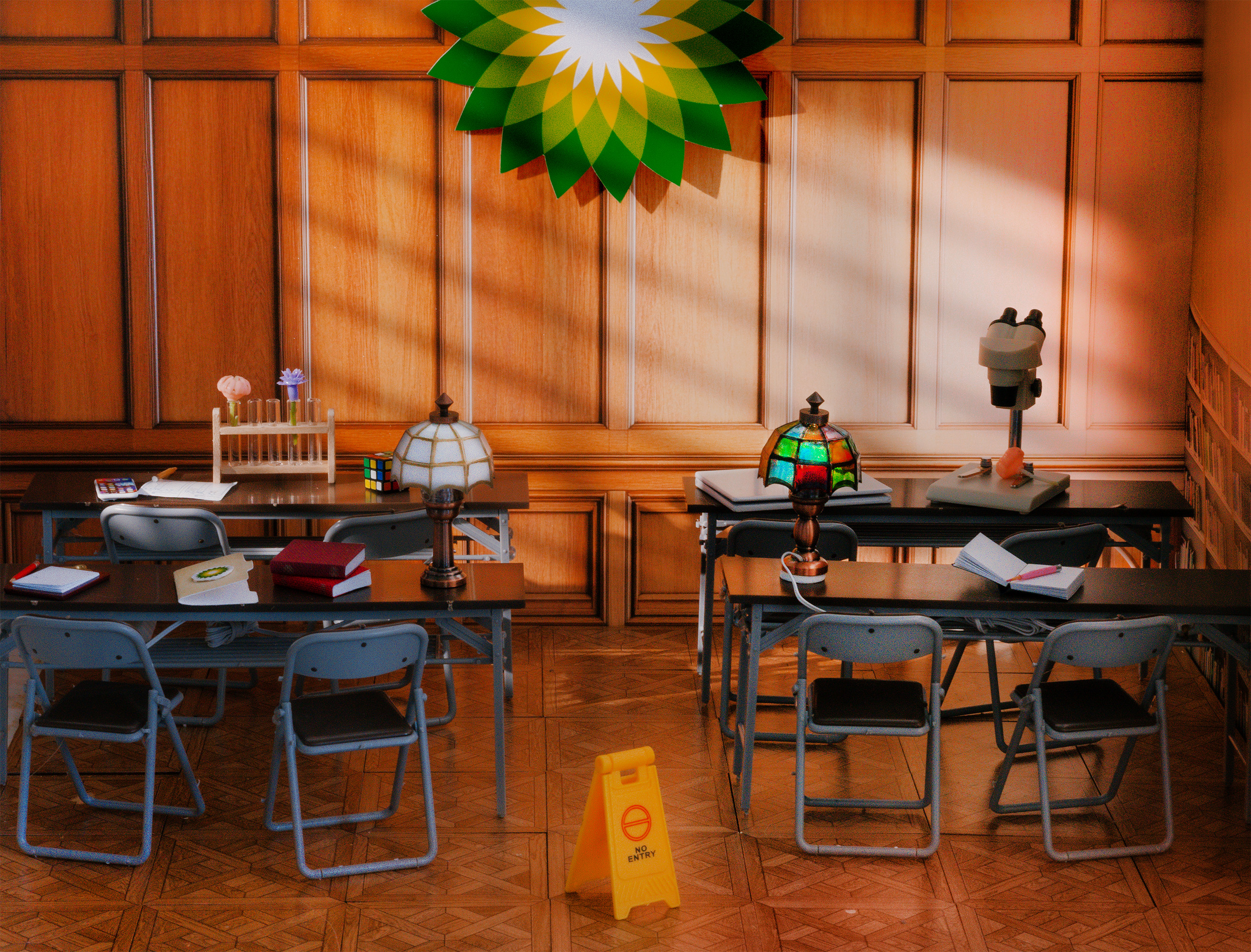 Rows of desks are lined up in a miniature library setting. The sun shines on the wooden walls, casting a shadow on the BP logo hung there.