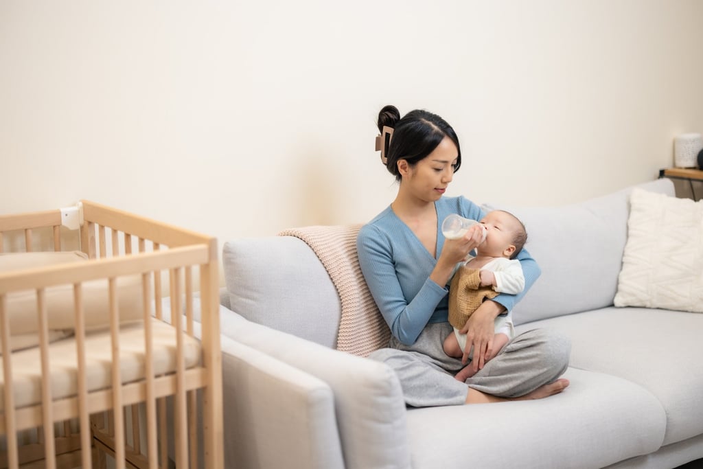 A mother feeds her newborn baby with milk from a bottle at home. Photo: Shutterstock