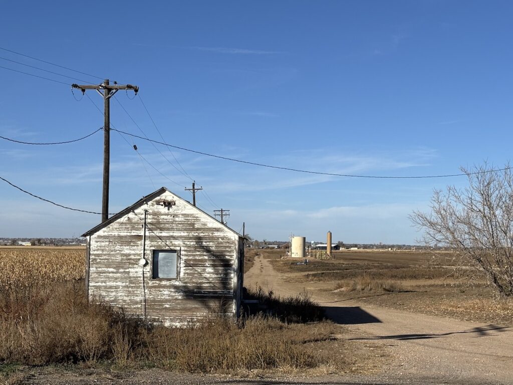 A small weather-worn building, left, with a road leading past oil and gas storage infrastructure awaiting cleanup.