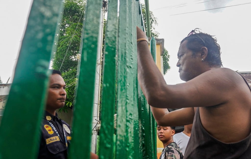 People look through the gates of San Jose National High School in Tacloban City, Leyte province, the Philippines, on Monday, following a shooting incident. Photo: EPA People look through the gates of San Jose National High School in Tacloban City, Leyte province, the Philippines, on Monday, following a shooting incident. Photo: EPA