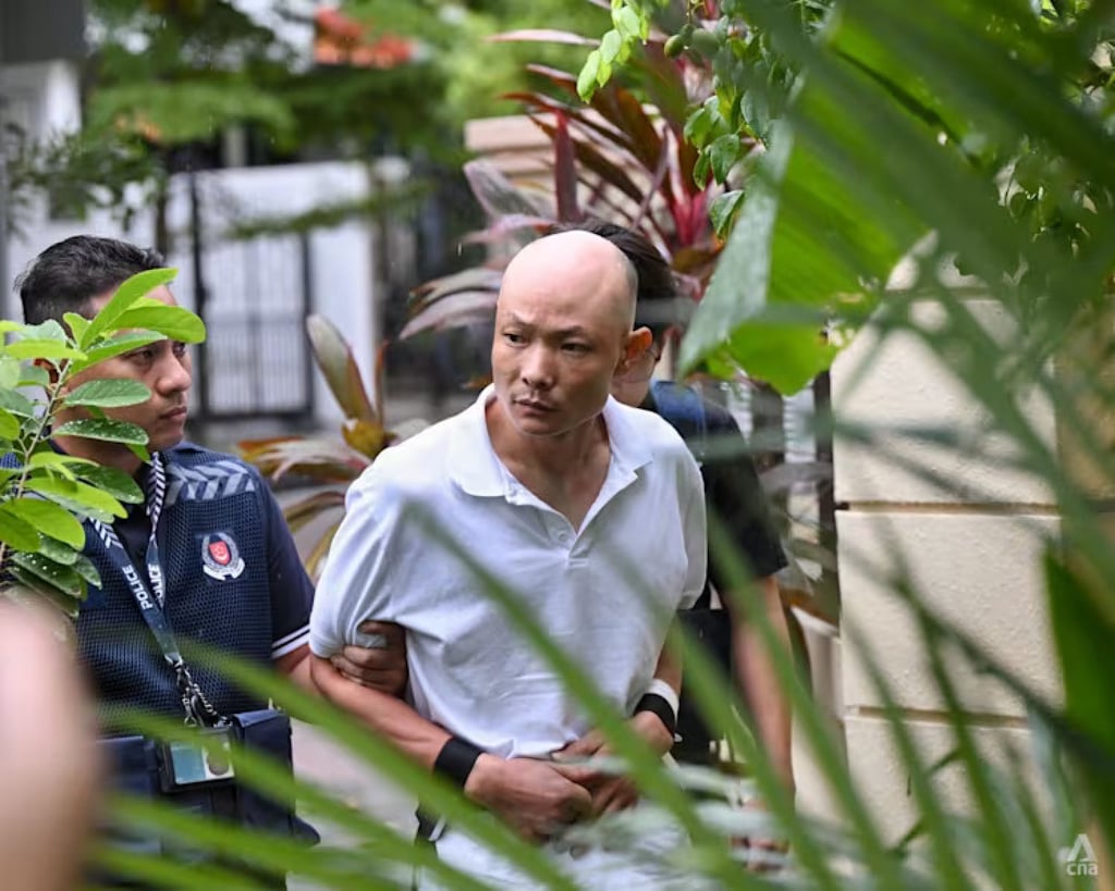 Huang Xiaozong being escorted by police officers along residential units in Serangoon in December 2025. Photo: CNA Huang Xiaozong being escorted by police officers along residential units in Serangoon in December 2025. Photo: CNA