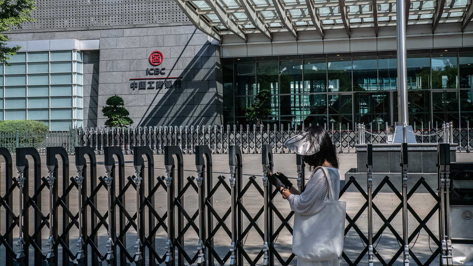 Photo of a woman walking past the ICBC headquarters in Beijing.