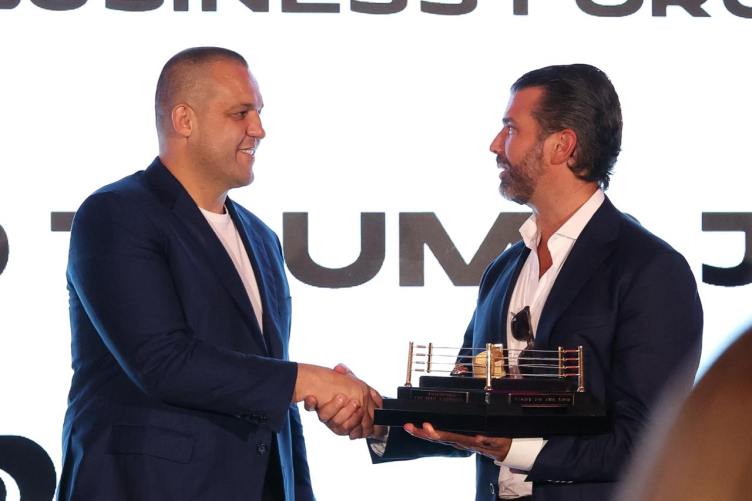 Umar Kremlev shakes hands with Donald Trump Jr., who is holding a model of a boxing ring.