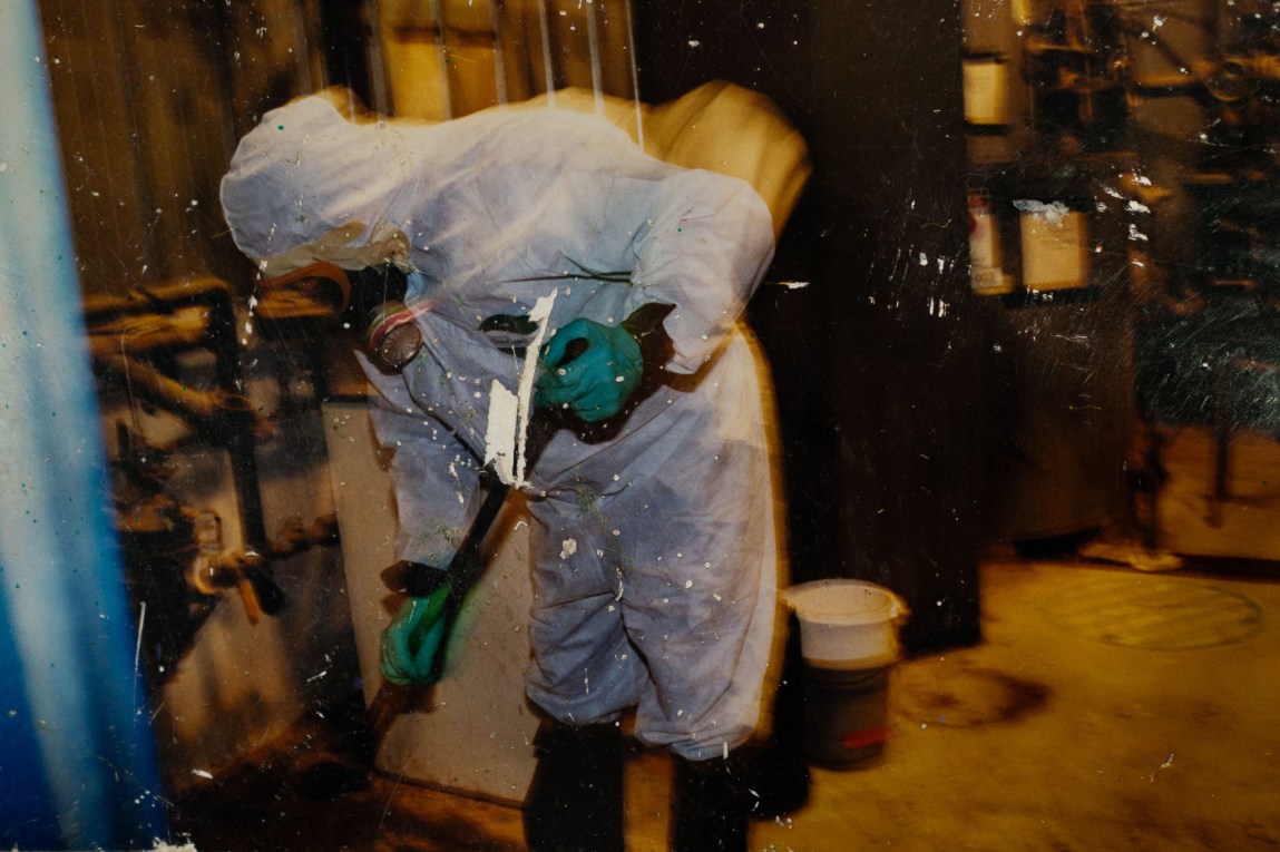 A scuffed-up photo of a man in a hazmat suit cleaning.
